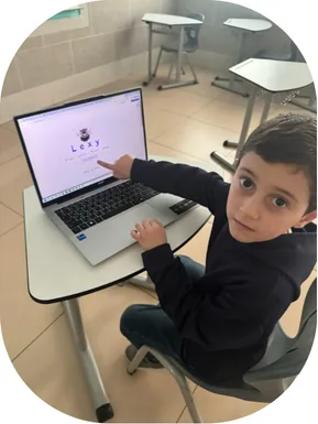طالب يشير إلى واجهة Lexy على حاسوب محمول داخل الصف.